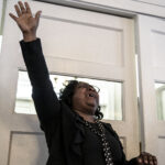 a woman dressed in all black has one arm raised above her head, she is cheering with joy